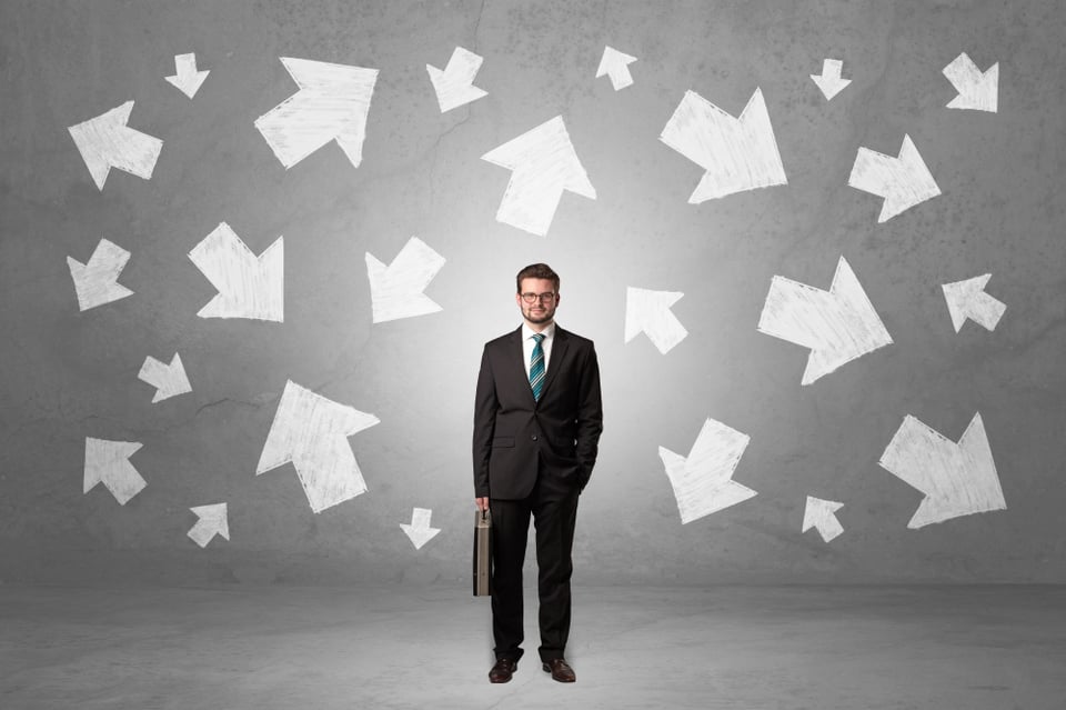 Handsome businessman standing in front of a wall with chalk drawn arrows